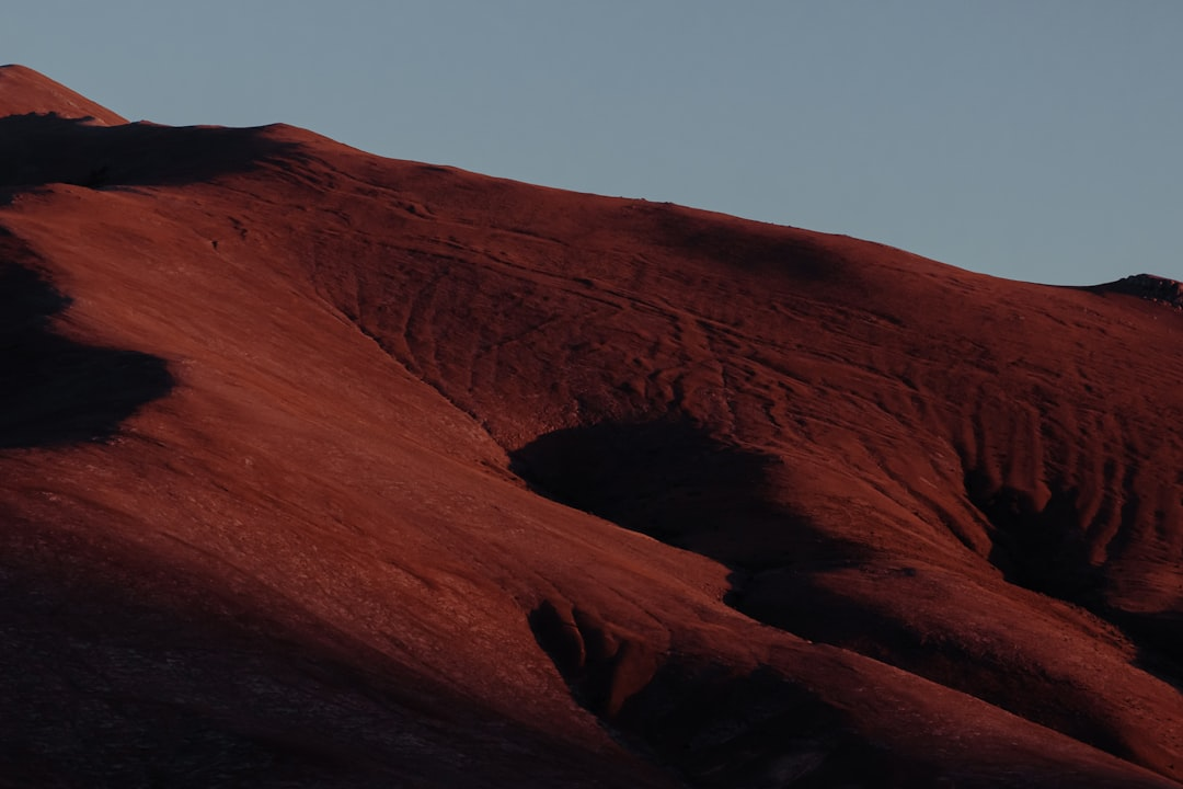 An astronaut in a futuristic spacesuit carefully studying a vibrant, crystalline alien rock formation on a rugged exoplanet surface, with a distant ringed gas giant dominating the alien sky.