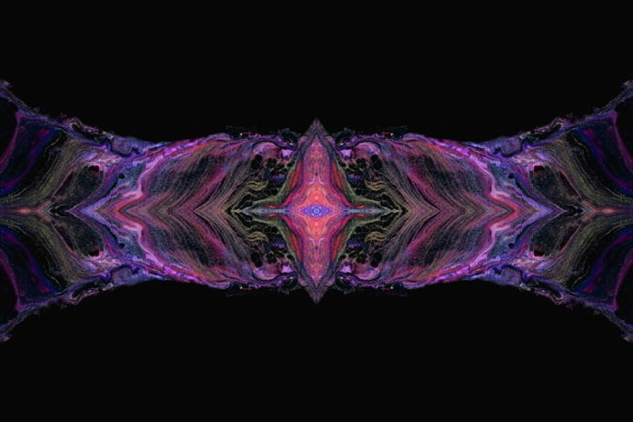 Vibrant, symmetrical abstract art depicts swirling streams of purple, gold, and red fluid converging on a glowing, star-like central core against a dark cosmic background, representing a challenging cosmological anomaly.