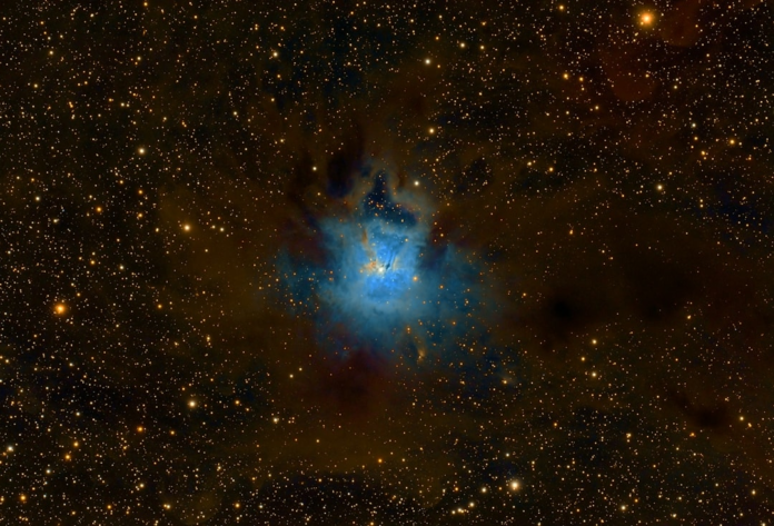 Brilliant blue and teal cosmic nebula, centered within a vast field of golden stars and dark interstellar dust, evoking the universe's mysterious origins.