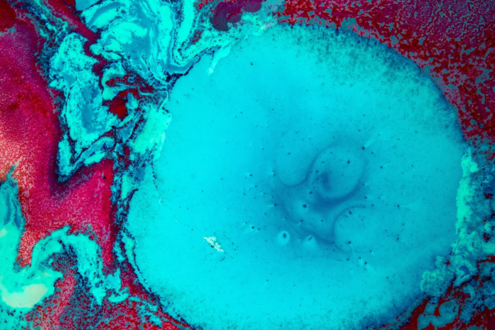 Dynamic abstract cosmic image featuring swirling vibrant blue and deep red, suggesting a black hole's formation or a dying star's turbulent remnants.