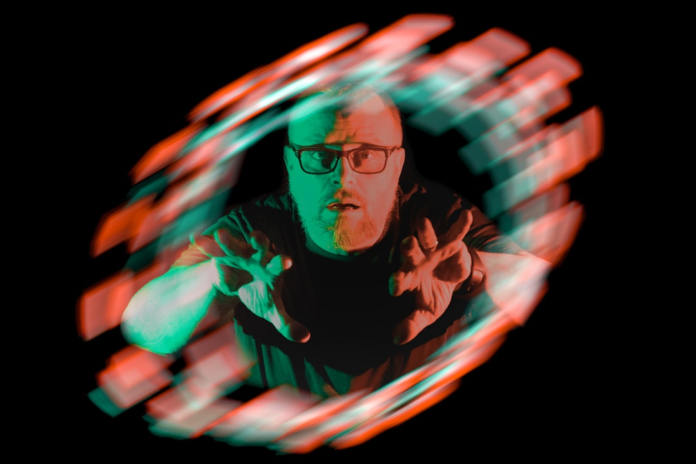 A man, looking surprised, reaches through a dynamic vortex of red and teal light, symbolizing the intense power and cosmic distortion of a black hole's influence.