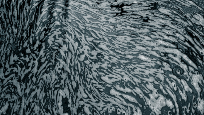 Intricate patterns of swirling white foam and dark water illustrate complex fluid dynamics and potential micro-vortices.