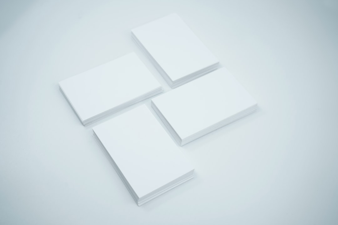 Four neat stacks of blank white business cards are meticulously arranged on a clean, minimalist white surface, suggesting a pristine, undeveloped potential or a foundational simplicity.