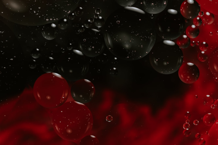 Close-up of vibrant red and dark gray bubbles with sparkling effervescence, representing the dynamic microscopic world of fermentation.