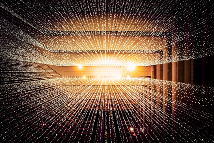 Thousands of interconnected golden light particles stretch across a vast dark space, converging towards a bright central glow, representing the flow of data and decentralized blockchain networks for Web3.