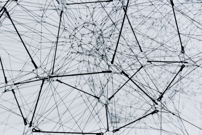 An intricate, abstract network of black lines and nodes against a light grey background, visually representing complex neural pathways and the evolving human brain.