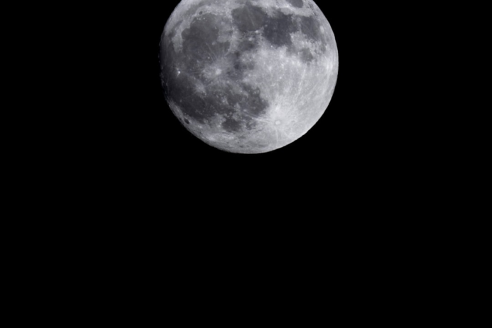 The detailed, cratered surface of the Moon is brightly illuminated against the deep blackness of space, evoking the immense distances involved in planetary travel.