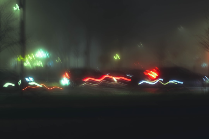 Vibrant streaks of red, green, and white light blur across a dark, indistinct background, powerfully conveying the immense velocity and dynamic motion of light speed travel.