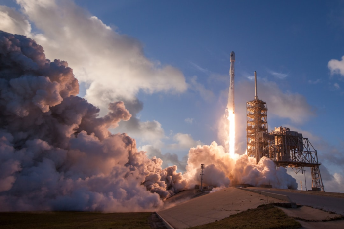 Powerful NASA Mars rocket launching from a concrete pad into a blue sky, enveloped by fiery exhaust and billowing smoke plumes, symbolizing future Red Planet missions.
