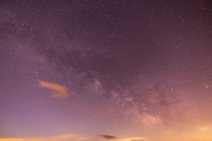Vast purplish-pink night sky densely packed with countless stars and the visible band of the Milky Way, illustrating cosmic coloration.