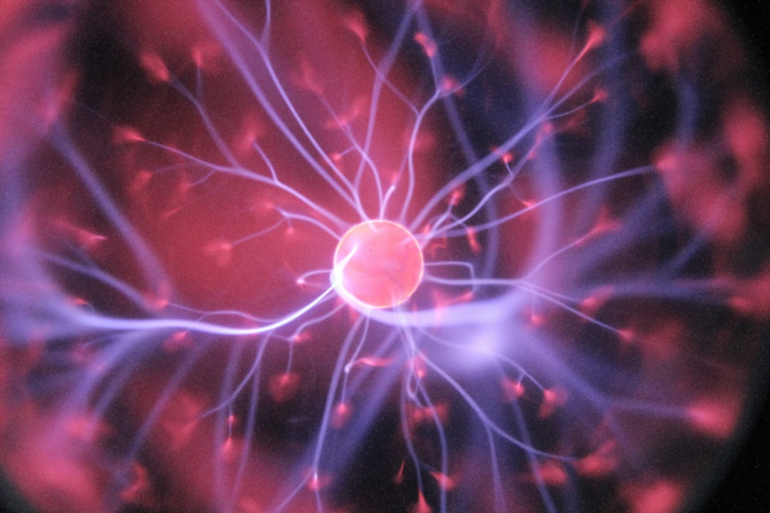 Close-up of a glowing plasma ball with energetic purple and pink electrical discharges, symbolizing the complex interactions of quantum physics and the universe.