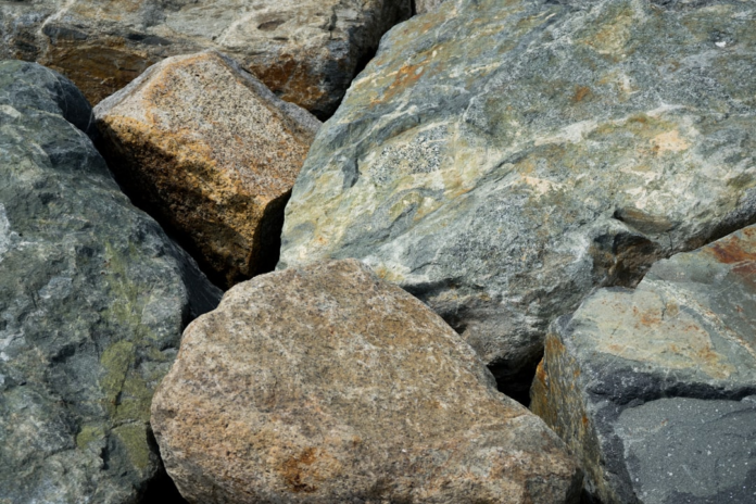 A close-up view of rugged, multicolored geological rock formations, highlighting the varied textures and mineral compositions critical for mapping Earth's structures in regional geology.