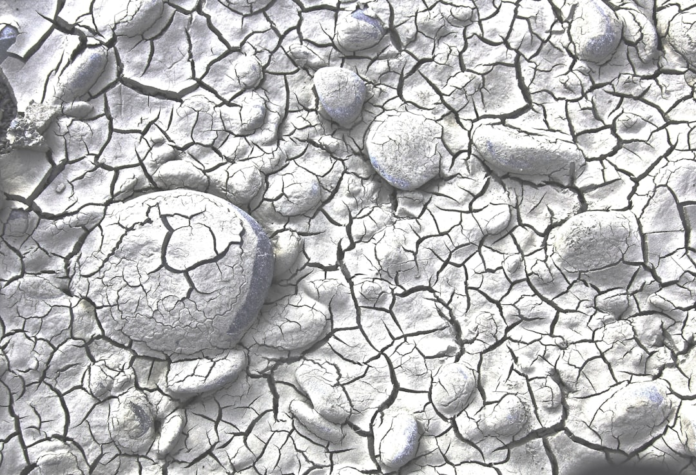 Dry, cracked earth with embedded rounded stones, illustrating the fractured surface of Earth's crust and tectonic plate movement.