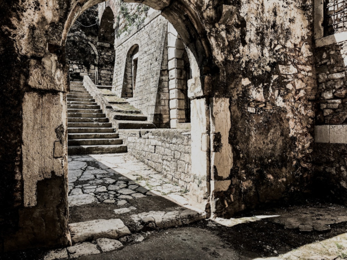 Weathered stone archways and ancient staircases recede into shadow, depicting the enduring, rugged beauty of a historic fort and evoking a timeless sense of discovery.